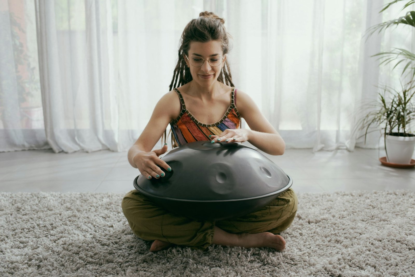 Woman playing a hang drum at home
